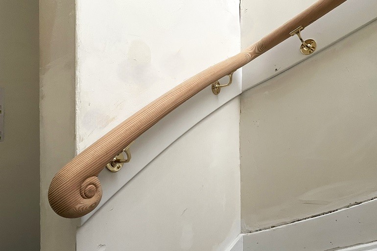 Ronde muurleuning op smetplank met houtsnijwerk eindstuk.