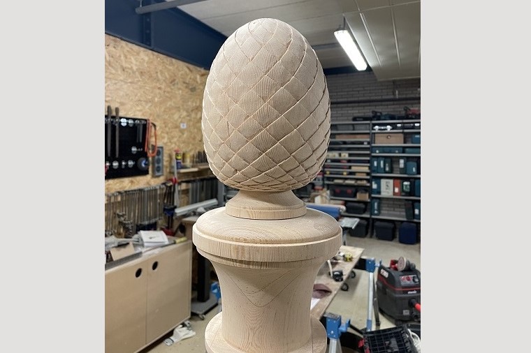 Snijwerk dennenappel op trappaal